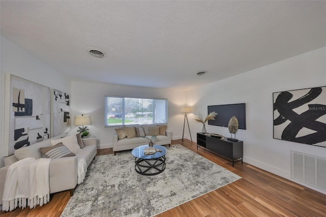 living area with wood finished floors, visible vents, and baseboards