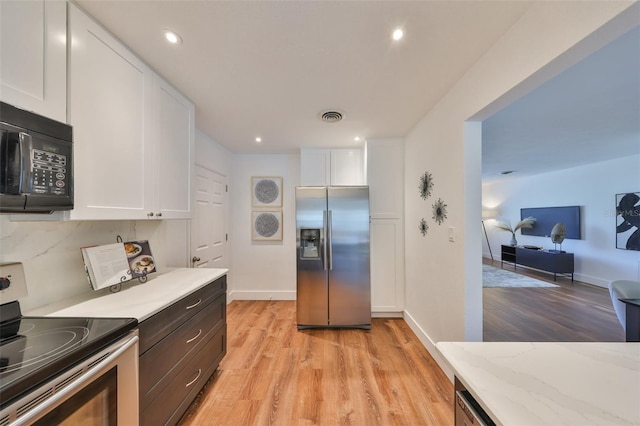 kitchen with appliances with stainless steel finishes, light wood-style flooring, visible vents, and white cabinetry