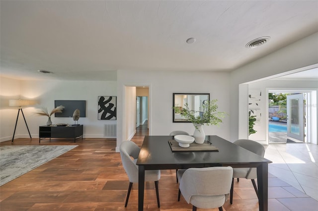 dining space with baseboards, visible vents, and wood finished floors