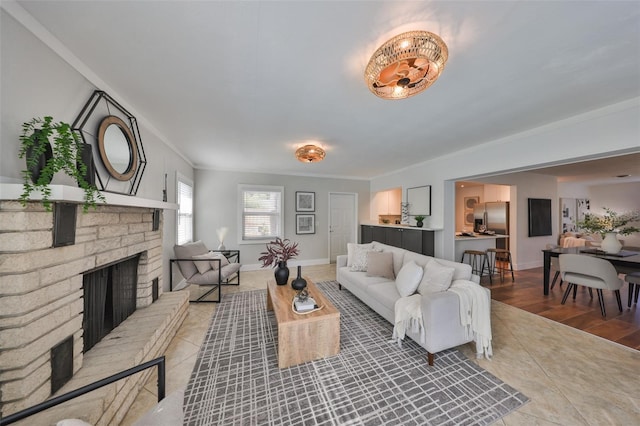 living room featuring ornamental molding, a brick fireplace, light tile patterned flooring, and baseboards