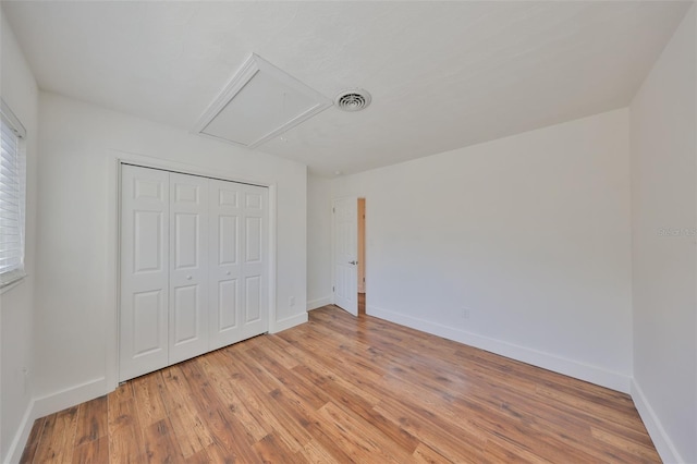 unfurnished bedroom with baseboards, light wood-type flooring, visible vents, and attic access