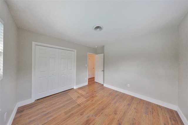 unfurnished bedroom featuring a closet, light wood-type flooring, visible vents, and baseboards