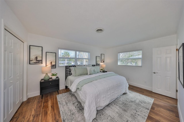 bedroom with dark wood-style floors, a closet, visible vents, and baseboards