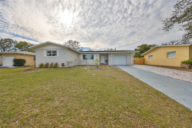 ranch-style home with an attached garage, fence, concrete driveway, and a front yard