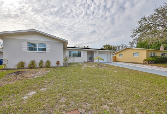 ranch-style home featuring an attached garage, driveway, a front lawn, and stucco siding