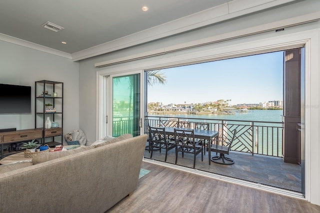 living area featuring recessed lighting, a water view, visible vents, ornamental molding, and wood finished floors