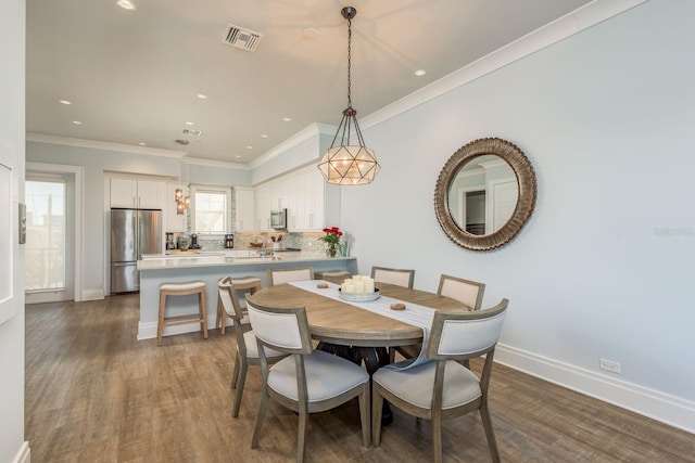 dining room featuring ornamental molding, dark wood-style flooring, visible vents, and baseboards