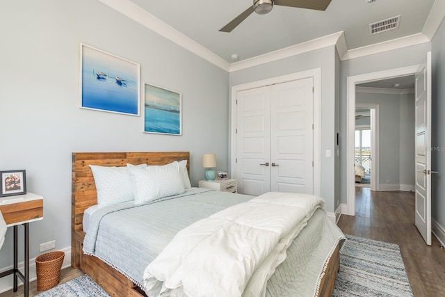 bedroom with baseboards, visible vents, dark wood finished floors, ornamental molding, and a closet