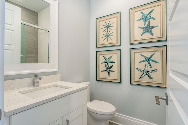 bathroom with a shower with door, vanity, and toilet