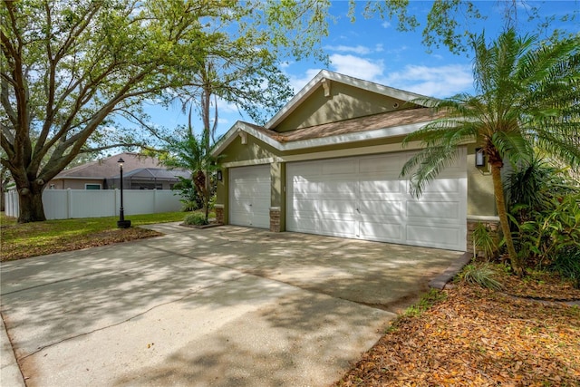 view of front of property with fence, driveway, stucco siding, a garage, and stone siding