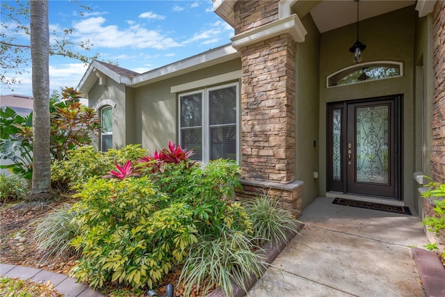 view of exterior entry featuring stucco siding and stone siding