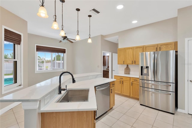 kitchen featuring visible vents, decorative light fixtures, a center island with sink, appliances with stainless steel finishes, and a sink