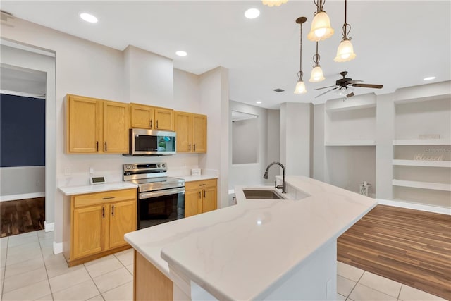 kitchen with a sink, light tile patterned floors, a ceiling fan, and stainless steel appliances