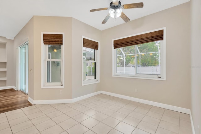 spare room featuring light tile patterned floors, baseboards, built in features, and a ceiling fan