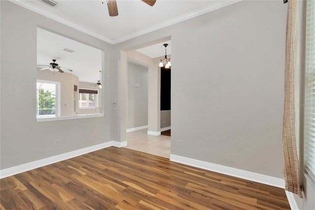 empty room featuring visible vents, wood finished floors, crown molding, baseboards, and ceiling fan