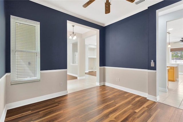 unfurnished room with visible vents, baseboards, wood finished floors, and ceiling fan with notable chandelier