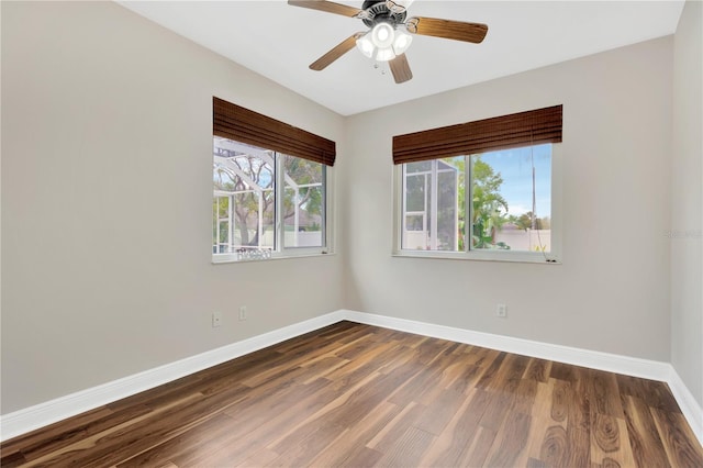 spare room featuring baseboards, dark wood-type flooring, and a ceiling fan