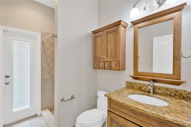 bathroom with vanity, toilet, tile patterned flooring, and a tile shower