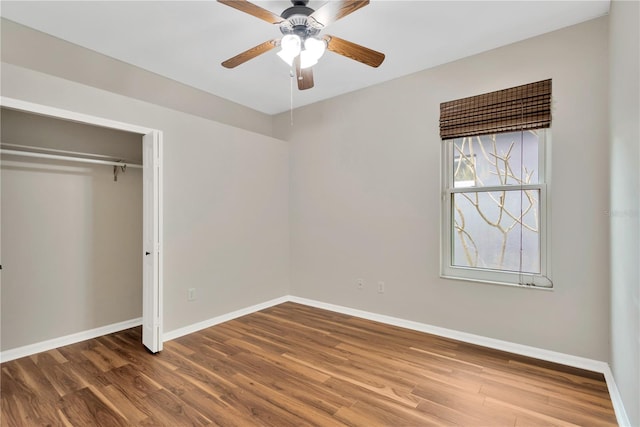 unfurnished bedroom featuring a ceiling fan, wood finished floors, baseboards, and a closet