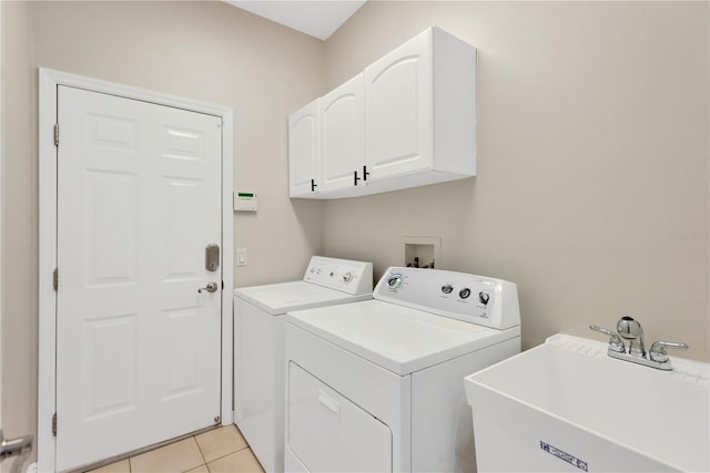 clothes washing area featuring light tile patterned floors, cabinet space, independent washer and dryer, and a sink