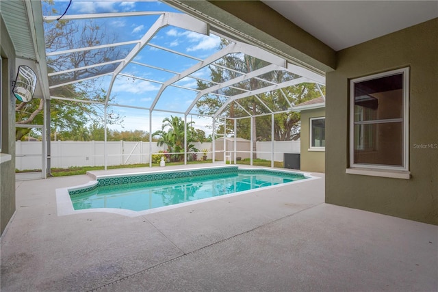 view of swimming pool with glass enclosure, a patio, a fenced backyard, and a fenced in pool