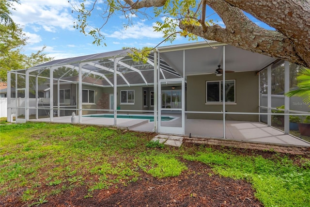 rear view of property with a patio area, stucco siding, a ceiling fan, and a fenced in pool