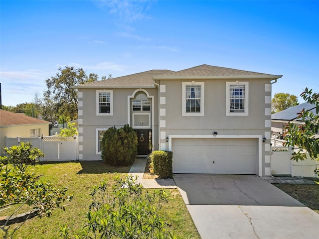 view of front of house featuring concrete driveway, fence, a front lawn, and stucco siding