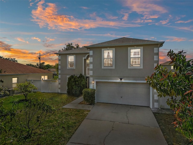 view of front facade featuring a yard, stucco siding, concrete driveway, an attached garage, and fence