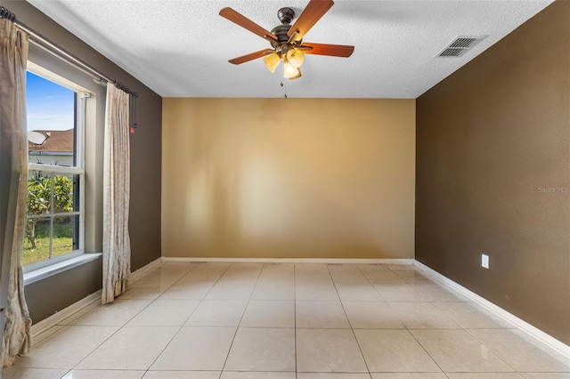 unfurnished room with ceiling fan, a textured ceiling, visible vents, and baseboards