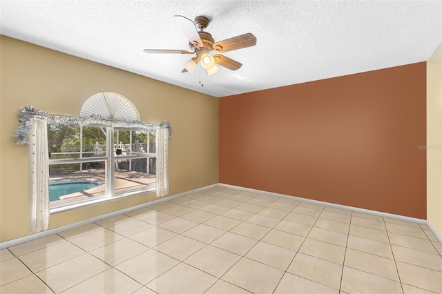 unfurnished room with light tile patterned floors, ceiling fan, baseboards, and a textured ceiling