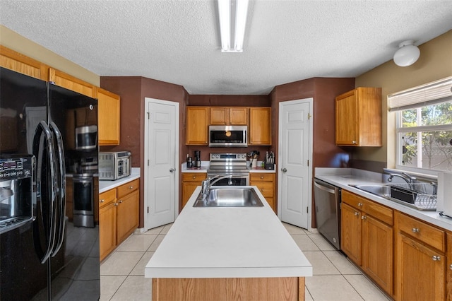 kitchen with an island with sink, appliances with stainless steel finishes, light countertops, and a sink