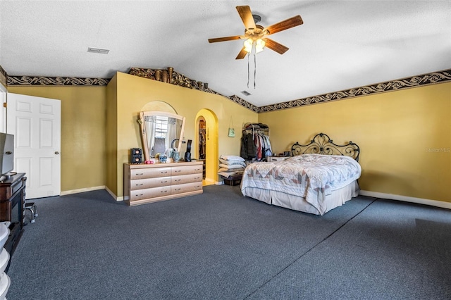 bedroom featuring arched walkways, lofted ceiling, visible vents, a textured ceiling, and baseboards