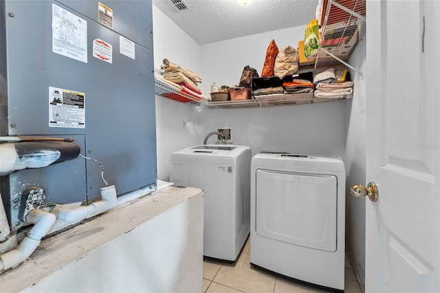 laundry area featuring heating unit, light tile patterned floors, washing machine and dryer, a textured ceiling, and laundry area