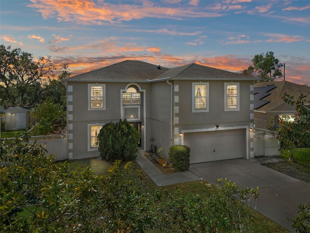 view of front of home with driveway, an attached garage, fence, and stucco siding