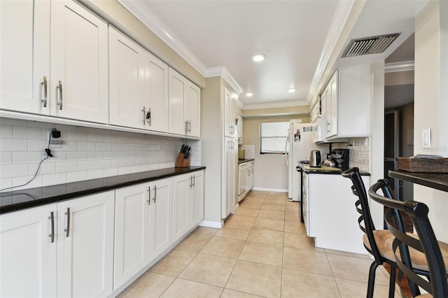 kitchen featuring light tile patterned flooring, visible vents, crown molding, and white cabinetry