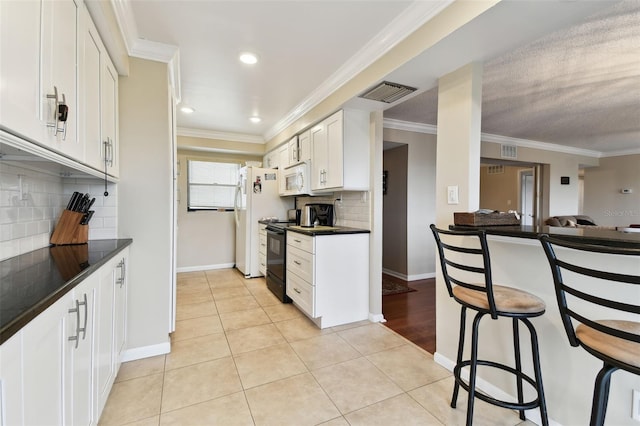 kitchen featuring light tile patterned floors, dark countertops, visible vents, white cabinetry, and white appliances