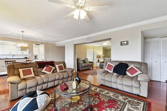 living area featuring a textured ceiling, visible vents, dark wood-style flooring, and ceiling fan with notable chandelier