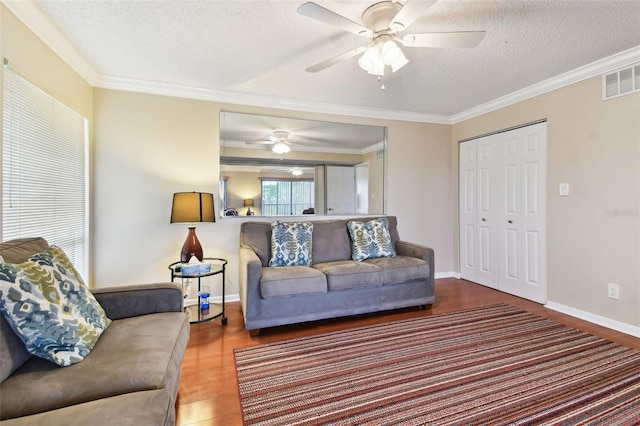 living room featuring a textured ceiling, visible vents, wood finished floors, and ornamental molding