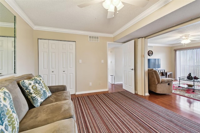 living area featuring a textured ceiling, dark wood-style flooring, visible vents, and crown molding