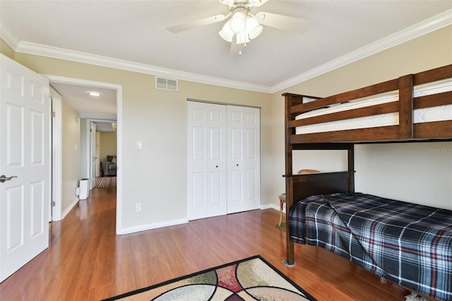 bedroom featuring ceiling fan, wood finished floors, visible vents, baseboards, and crown molding