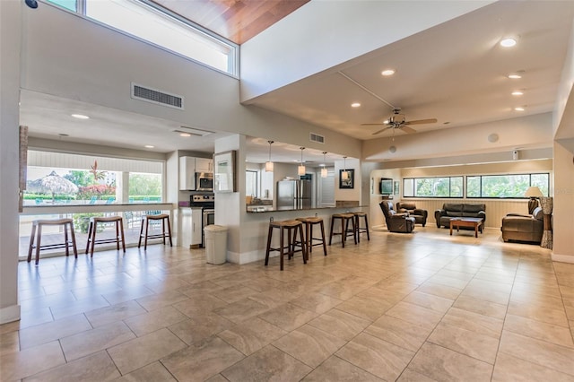 kitchen featuring stainless steel appliances, a peninsula, visible vents, white cabinetry, and open floor plan