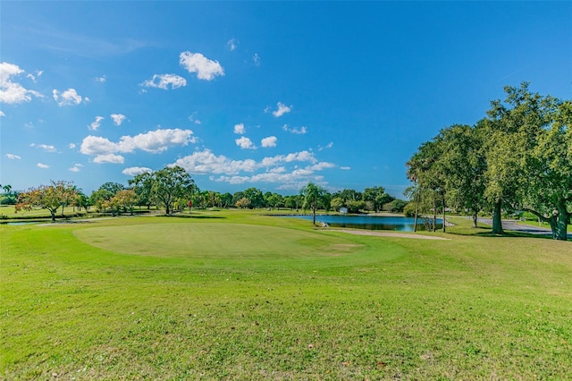 view of home's community with a water view, view of golf course, and a lawn