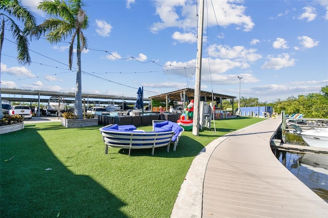 view of home's community featuring a water view, an outdoor living space, and a lawn