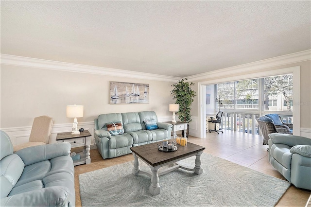 living area featuring light tile patterned flooring, wainscoting, a textured ceiling, and crown molding