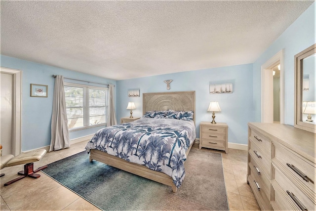 bedroom featuring light tile patterned flooring, baseboards, and a textured ceiling