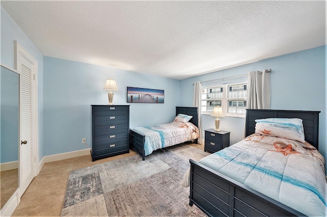 bedroom featuring light carpet, a textured ceiling, and baseboards