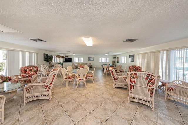 living room featuring light tile patterned flooring, visible vents, and plenty of natural light