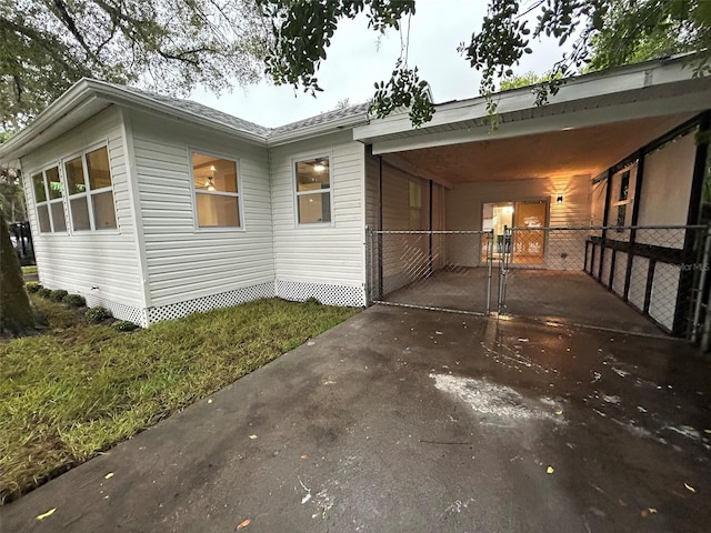 view of side of home with an attached carport, a gate, driveway, and fence