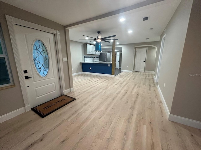 foyer entrance with light wood-style floors, baseboards, visible vents, and ceiling fan