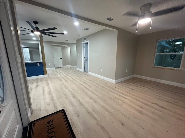 unfurnished room with light wood finished floors, visible vents, arched walkways, baseboards, and ceiling fan